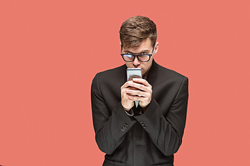 Image showing The young caucasian businessman on red background talking on cell phone