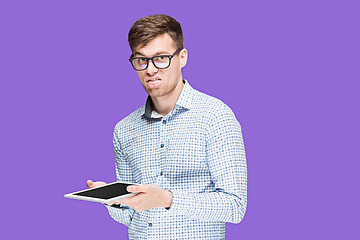 Image showing The young man in a shirt working on laptop on lilac backgroundin