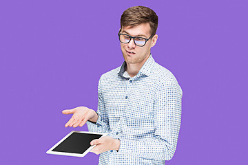 Image showing The young man in a shirt working on laptop on lilac backgroundin