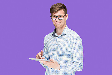 Image showing The young man in a shirt working on laptop on lilac backgroundin