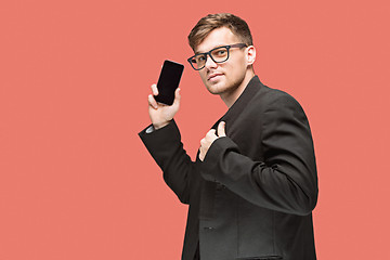 Image showing The young caucasian businessman on red background talking on cell phone