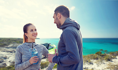 Image showing smiling couple with bottles of water outdoors
