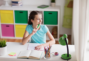 Image showing happy girl with book writing to notebook at home