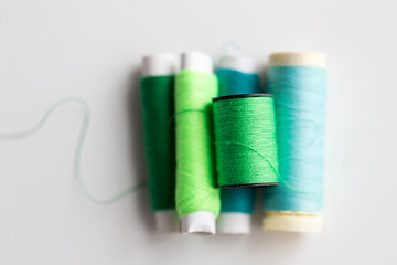 Image showing green and blue thread spools on table