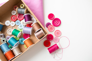 Image showing box with thread spools and sewing buttons on table