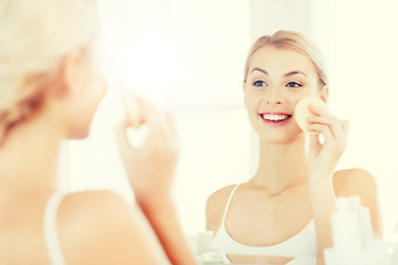 Image showing young woman washing face with sponge at bathroom