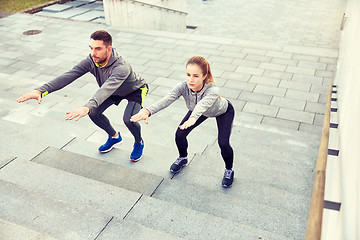 Image showing couple doing squats on city street stairs