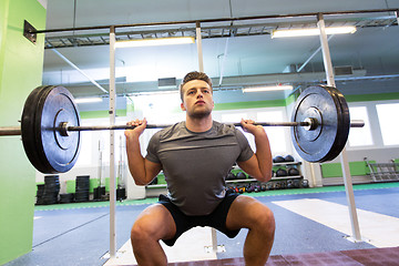 Image showing young man flexing muscles with barbell in gym