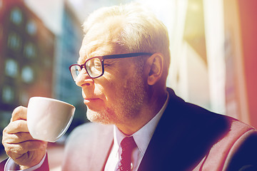 Image showing senior businessman drinking coffee on city street