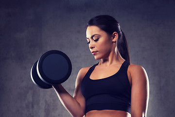 Image showing young woman flexing muscles with dumbbells in gym