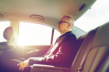 Image showing senior businessman driving on car back seat