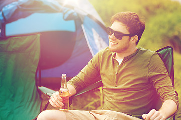 Image showing happy young man drinking beer at campsite tent