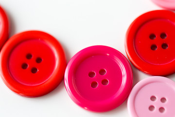 Image showing red and pink sewing buttons on white background