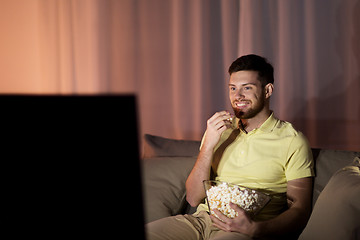 Image showing happy man with popcorn watching tv at night