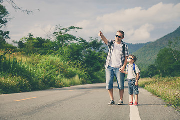 Image showing Father and son walking on the road.