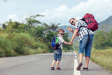 Image showing Father and son walking on the road.