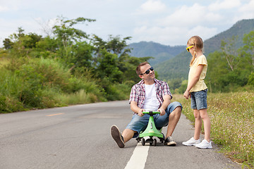 Image showing Father and daughter playing on the road.