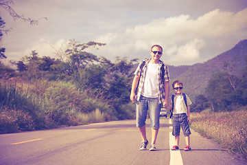 Image showing Father and son walking on the road.