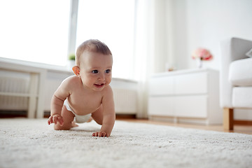 Image showing little baby in diaper crawling on floor at home