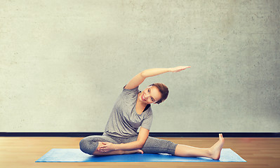 Image showing happy woman making yoga and stretching on mat