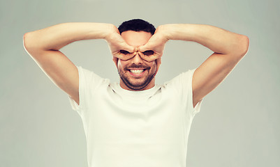 Image showing man making finger glasses over gray background