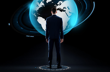 Image showing businessman with earth globe hologram over black
