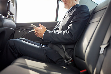 Image showing senior businessman texting on smartphone in car