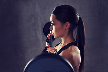 Image showing young woman flexing muscles with barbell in gym
