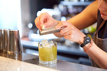 Image showing bartender grates chocolate to cocktail at bar