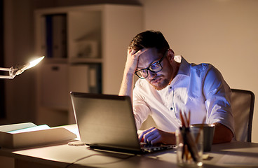 Image showing businessman with laptop thinking at night office