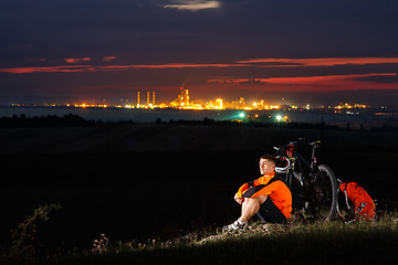 Image showing Biker resting on top of mountain with his bicycle