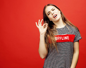 Image showing young pretty emitonal posing teenage girl on bright red background, happy smiling lifestyle people concept 