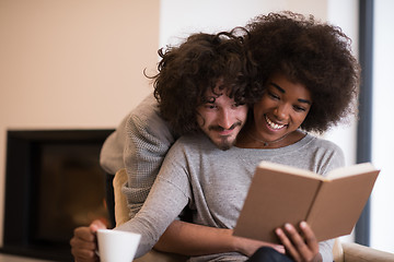 Image showing multiethnic couple hugging in front of fireplace