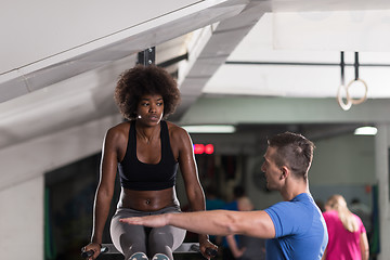 Image showing black woman doing parallel bars Exercise with trainer