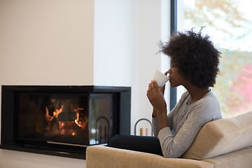 Image showing black woman drinking coffee in front of fireplace