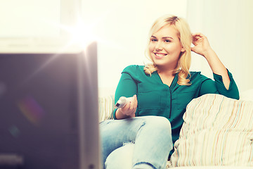 Image showing smiling woman with remote watching tv at home