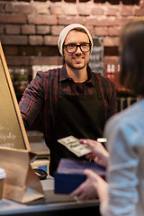 Image showing happy barman and woman paying money at cafe