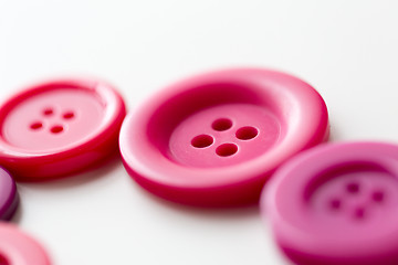 Image showing red and pink sewing buttons on white background