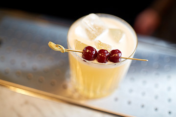 Image showing glass of cocktail with cherries at bar