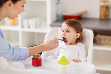 Image showing happy mother feeding baby with puree at home