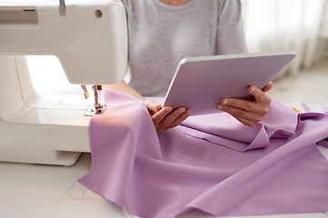 Image showing tailor with sewing machine, tablet pc and fabric