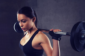 Image showing young woman flexing muscles with barbell in gym