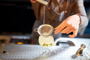 Image showing woman bartender pouring cocktail into glass at bar