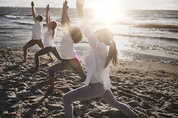 Image showing group of people making yoga exercises on beach