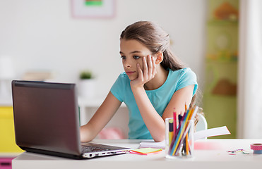 Image showing bored girl with laptop and notebook at home