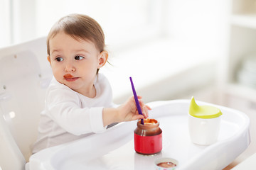 Image showing baby with spoon eating puree from jar at home