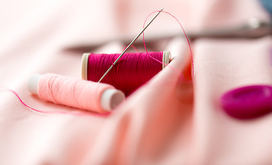 Image showing sewing needle, spools of thread and cloth