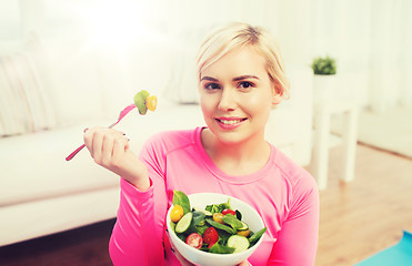 Image showing smiling young woman eating salad at home