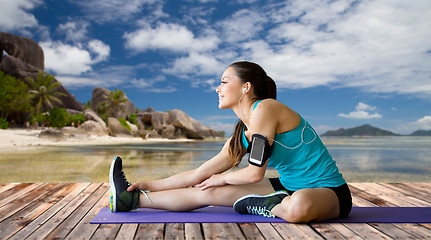 Image showing woman with smartphone stretching leg on mat