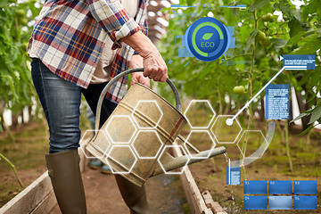 Image showing senior woman with watering can at farm greenhouse